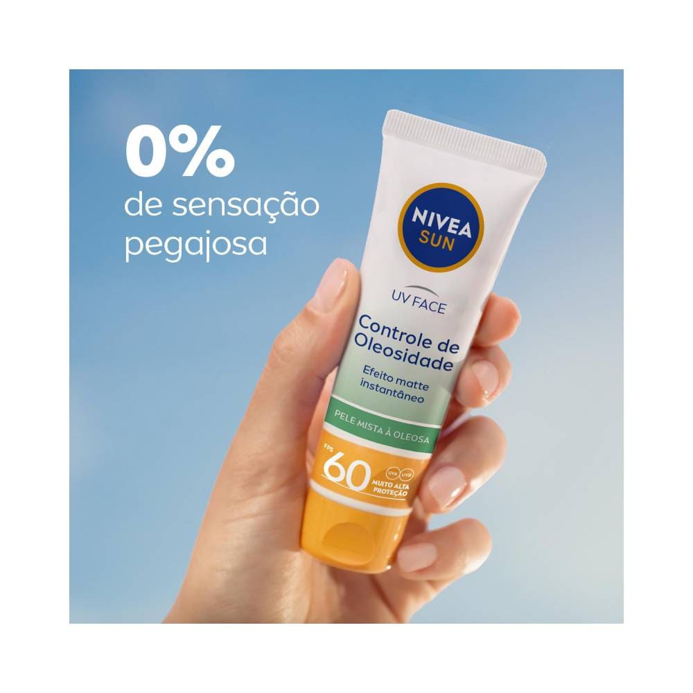 Mão segurando tubo do protetor solar Nivea Sun UV Face contra fundo azul