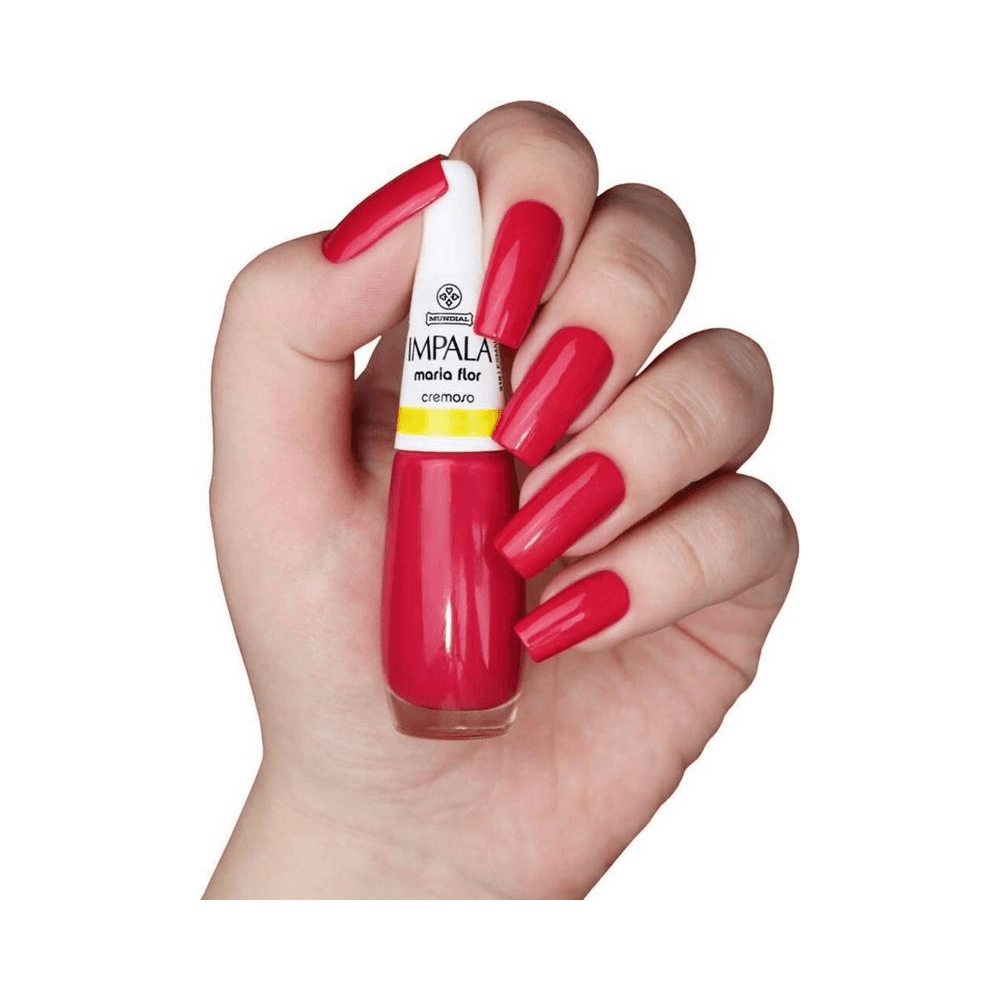 Mão segurando frasco Impala Maria Flor com unhas esmaltadas no mesmo tom vermelho