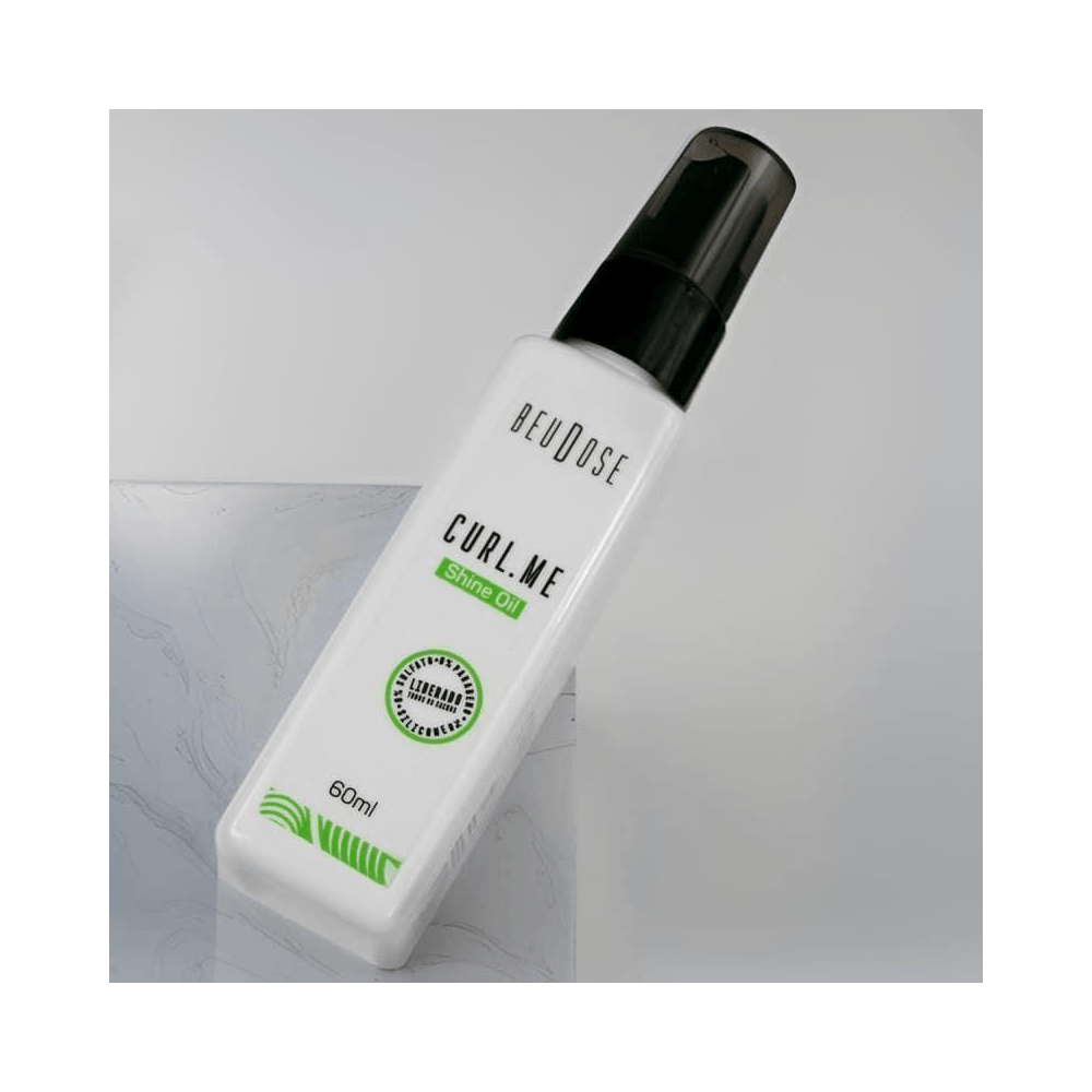 Frasco inclinado do Óleo Beudose Curl.Me Shine 60ml sobre superfície marmorizada