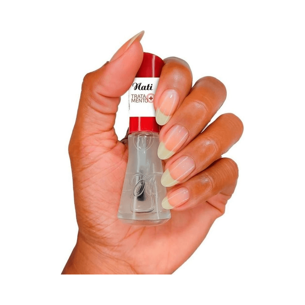 Mão segurando Base Nati Tratamento Óleo Secante com unhas naturais