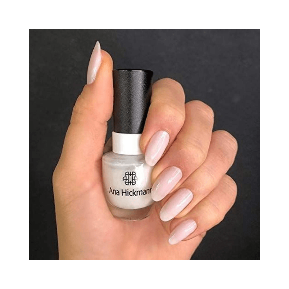 Mão segurando Esmalte Ana Hickmann Branquinho Loka com unhas esmaltadas