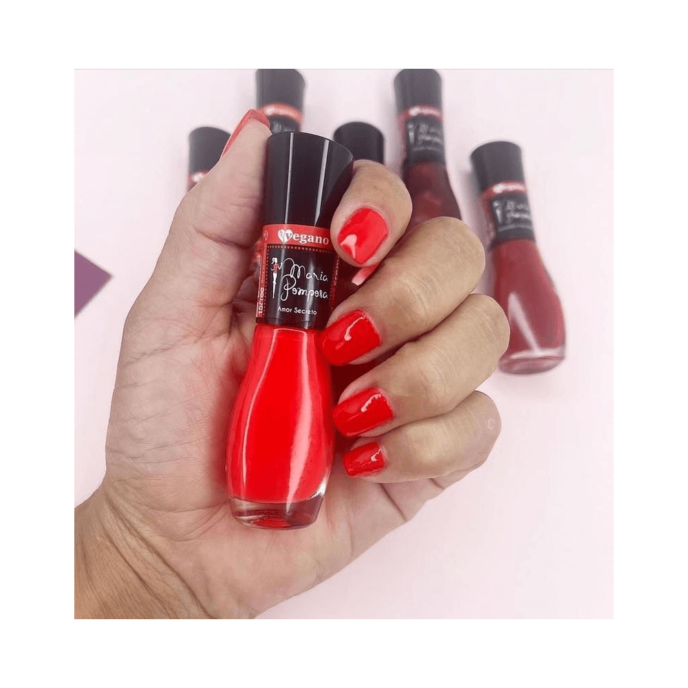 Mão segurando o frasco do esmalte Amor Secreto com unhas pintadas combinando